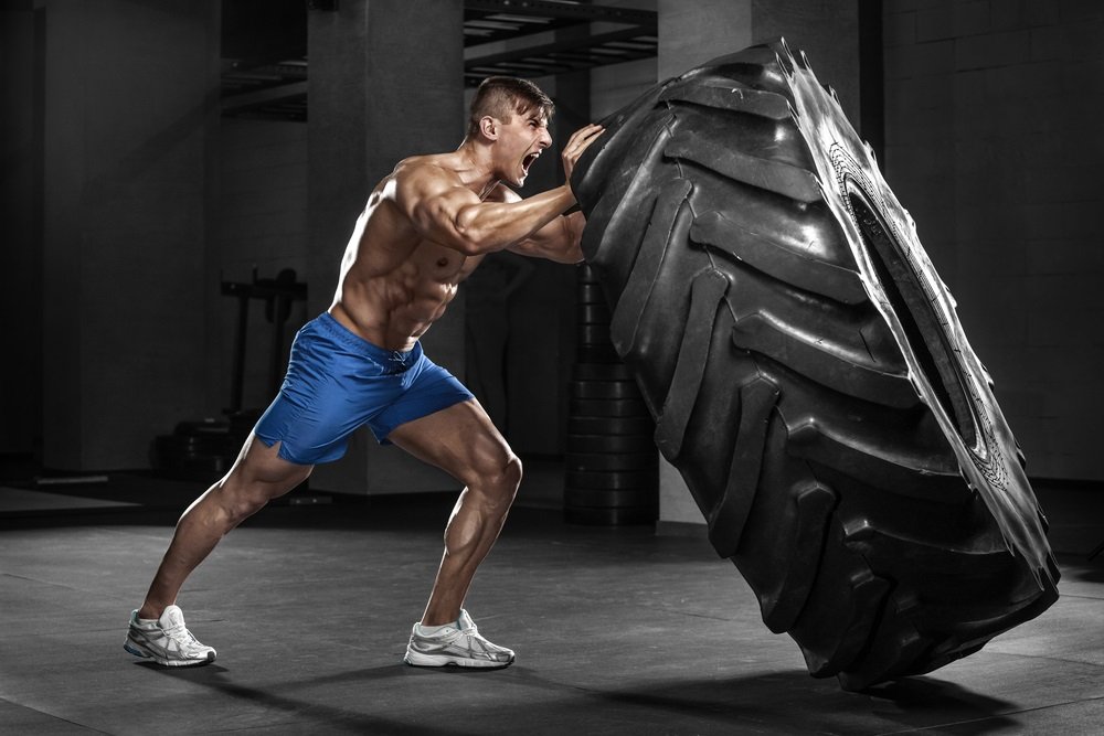 Muscular-man-working-out-in-gym-flipping-tire